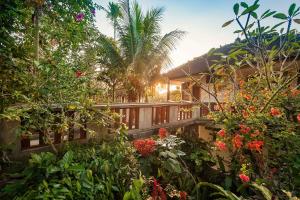 Ubud Inn Cottage by Prasi في أوبود: منزل به حديقة بها زهور وأشجار
