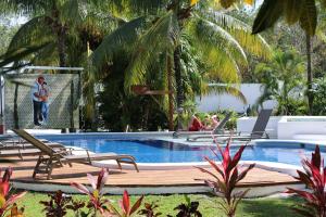 a pool with chairs and a man standing next to it at WishTulum in Tulum