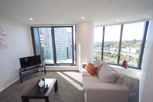 a living room with a couch and large windows at Fantastic 2 Bedroom Apartment with Sea Views in Auckland