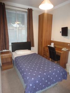 a bedroom with a bed and a desk and a window at Warwick Lodge in Kingston upon Thames