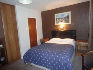 a hotel room with a bed with a blue comforter at Warwick Lodge in Kingston upon Thames