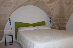 a bedroom with a white bed with a green headboard at Villa Colittacarrafa in Galatone