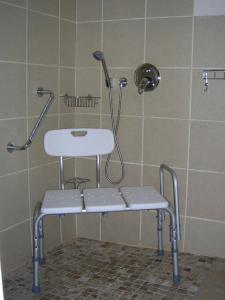 a shower with a white stool in a bathroom at Dempsey's Self-Catering Guest House in Port Elizabeth