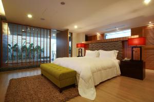 五結鄉的住宿－怡蘭精品旅館 ，卧室配有一张白色大床和绿色长凳