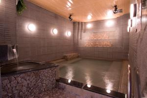 a hot tub in a bathroom with a stone wall at Refre Forum in Tokyo