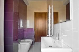 y baño con lavabo, aseo y azulejos púrpura. en inStile aparthotel, en Ascea
