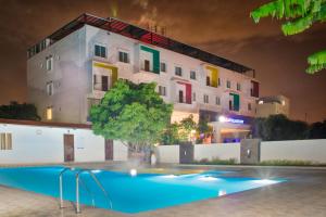 a building with a swimming pool in front of a building at RG Hotels and Resort in Mālūr