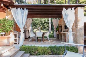 a patio with white curtains and a table and chairs at Naftilos Villa Sani with private Pool in Sani Beach