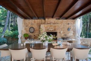 a dining room with a table and chairs and a stone fireplace at Naftilos Villa Sani in Sani Beach