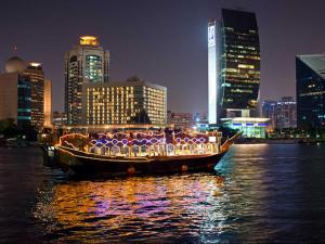 ein Boot mit Lichtern auf dem Wasser in einer Stadt in der Unterkunft Arabian Courtyard Hotel & Spa in Dubai