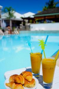 un plato de cruasanes y dos vasos de zumo de naranja en Hôtel Les Créoles en Saint-Gilles-les-Bains