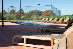 a row of benches sitting next to a swimming pool at Potters Apartments in Cessnock