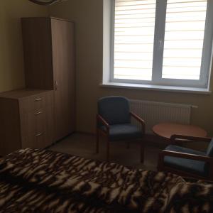 ein Schlafzimmer mit einem Bett, einem Stuhl und einem Fenster in der Unterkunft Svečių namai in Ryškėnai