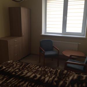 a bedroom with a bed and a chair and a window at Svečių namai in Ryškėnai