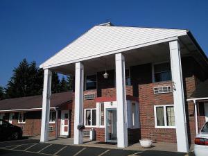 a large brick building with white columns at Colonial Inn Mercer-Grove City in Mercer