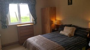 una camera con un letto con una finestra e un comò di Divine Mercy B&B a Knock