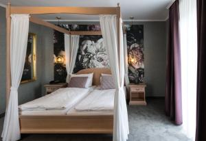 a bedroom with a canopy bed with flowers on the walls at Hotel Germania in Cochem +50 photos