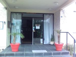 uma entrada para um edifício de escritórios com dois vasos de plantas em Hotel Restaurant Le Manguier em Peyrat-de-Bellac