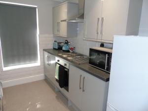 a kitchen with white cabinets and a stove and a microwave at Jeffersons Hotel & Serviced Apartments - The Steel Works in Barrow in Furness +15 photos