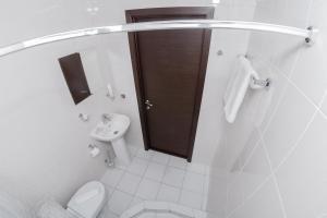 a white bathroom with a toilet and a sink at Vash Hotel in Yekaterinburg