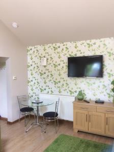 a room with a table and a television on a wall at The Annex Apartment is on Cheddar Bridge Apartments in Cheddar