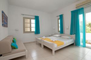 a white bedroom with blue curtains and a bed and a couch at Villa Stella Apartments by Estia in Stalís +55 photos