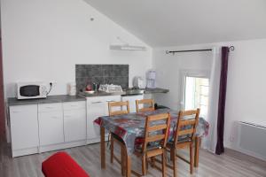 una cucina con tavolo e sedie e una cucina con mobili bianchi di L'oiseau bleu a Salin-de-Giraud