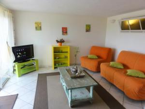 a living room with an orange couch and a tv at Gîtes Les 3 Cigales in Vallon-Pont-dʼArc