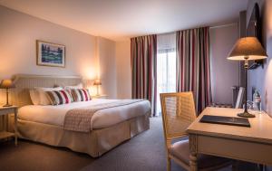 a hotel room with a bed and a desk and a desk at Best Western Plus Hostellerie Du Vallon in Trouville-sur-Mer