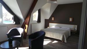 a bedroom with a bed and a chair and a table at Le Relais de la Pointe du Van in Cléden-Cap-Sizun