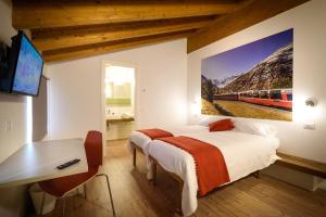 ティラーノにあるLe stanze del Trenino Rossoのベッド2台とデスクが備わる客室で、壁に電車の絵画が飾られています。