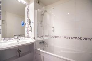a white bathroom with a sink and a shower at Best Western Plus Hostellerie Du Vallon in Trouville-sur-Mer