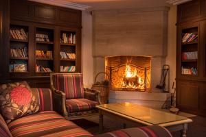 a living room with a fireplace and a couch and a table at Best Western Plus Hostellerie Du Vallon in Trouville-sur-Mer
