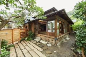 uma casa de madeira com um alpendre e uma árvore em Minato-no Akari em Hayama