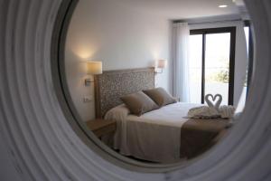 a mirror reflecting a bedroom with a bed and a window at Hotel Rosamar - Emar Hotels in Es Pujols +37 photos
