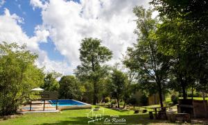 a swimming pool with a picnic table and trees at Posada La Rosita in Santa Rosa de Calamuchita