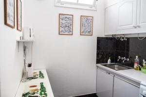 uma cozinha branca com um lavatório e um balcão em Cosy Flat in City Center em Ponta Delgada