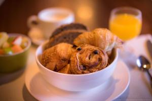 a bowl of pastries on a plate with a glass of orange juice at Best Western Plus Hostellerie Du Vallon in Trouville-sur-Mer