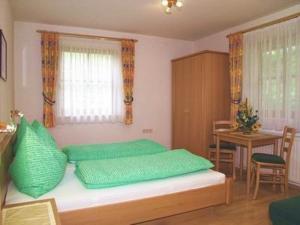 sypialnia z łóżkiem z zielonymi poduszkami i stołem w obiekcie Appartement Jackie Eschbacher w mieście Wagrain