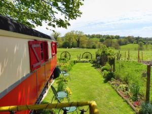 a red train parked in a garden with chairs at La Roulotte De Lola - Chambre d'hôtes in La Celle