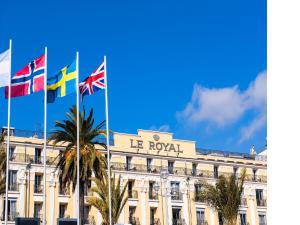a building with three flags in front of it at Hôtel Le Royal Promenade des Anglais in Nice