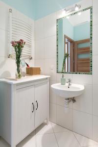 a white bathroom with a sink and a mirror at Blue Sky Apartment in Krakow