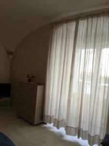 1 dormitorio con ventana con cortinas blancas y vestidor en My suite Sorrento, en Sorrento