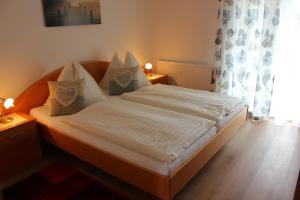Schlafzimmer mit einem Bett mit weißer Bettwäsche und Kissen in der Unterkunft Kusternighof in Velden am Wörthersee