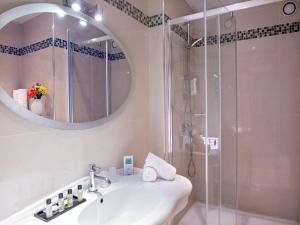 a bathroom with a sink and a shower with a mirror at Hôtel Le Royal Promenade des Anglais in Nice