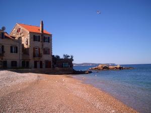 a building on a beach next to the water at Kod Senke in Komiža