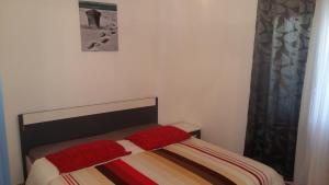 a bed with two red pillows on it in a bedroom at Apartman Sara in Dugi Rat