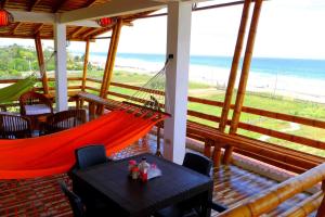 a hammock on a porch with a view of the beach at Hotel Sotavento in Montañita