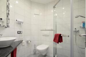 a bathroom with a toilet and a sink and a shower at Hotel Engelhorn in Leimen