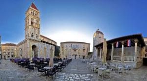 a courtyard with tables and chairs and a clock tower at Apartment Sunset in Trogir